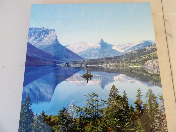 Color photograph of a serene mountain lake with clear blue skies, reflecting rugged peaks and green forest, showcasing natural beauty.