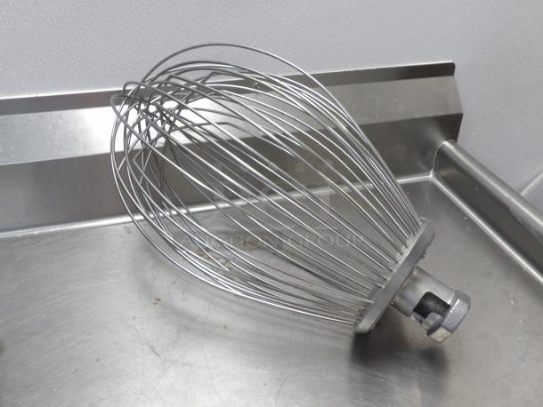 Stainless steel wire whisk for 80qt Hobart mixer, metal construction, used condition, shown on a metal surface.