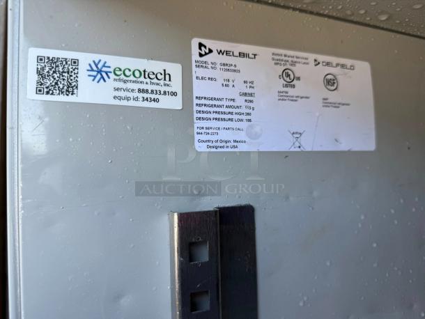 Delfield GBR2P-S commercial fridge tag details, showing brand, model, serial number, power specs, and service contact info.