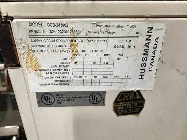Hussmann DCB-243662 Refrigerated Merchandiser data plate showing model, serial number, voltage specs, and UL certification.
