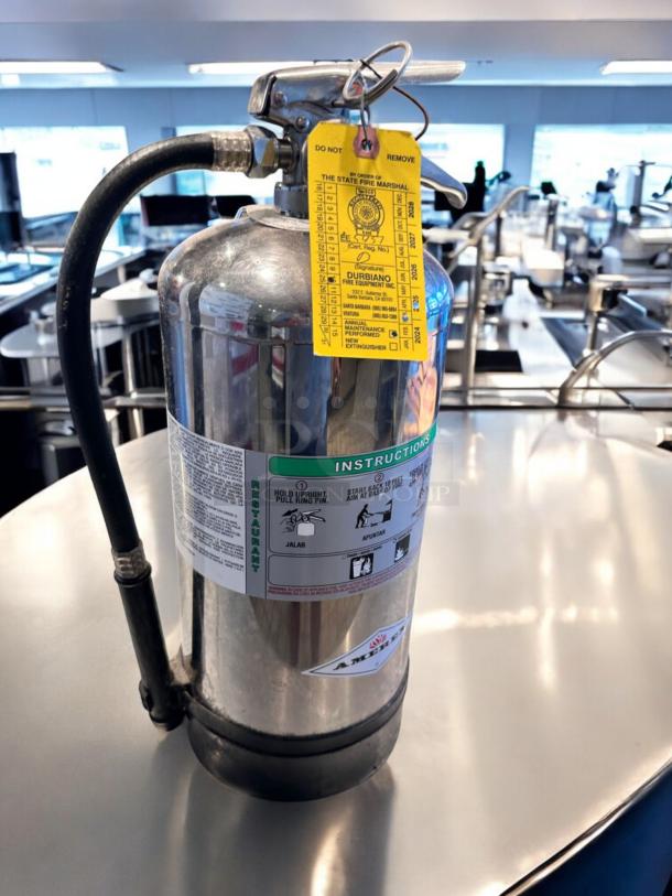 AMEREX Model 240 K-Class fire extinguisher, stainless steel, top-tier condition, fully inspected with inspection tag visible.