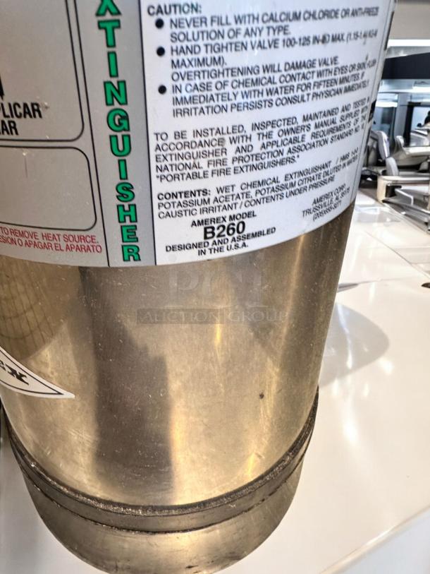 AMEREX K-Class fire extinguisher, Model 240, stainless steel, inspected, tagged, with a visible caution label.