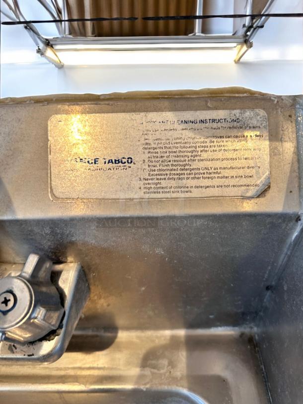 Advance Tabco stainless steel hand sink with faucet and side splashes, wall-mounted; label shows cleaning instructions, immaculate condition.