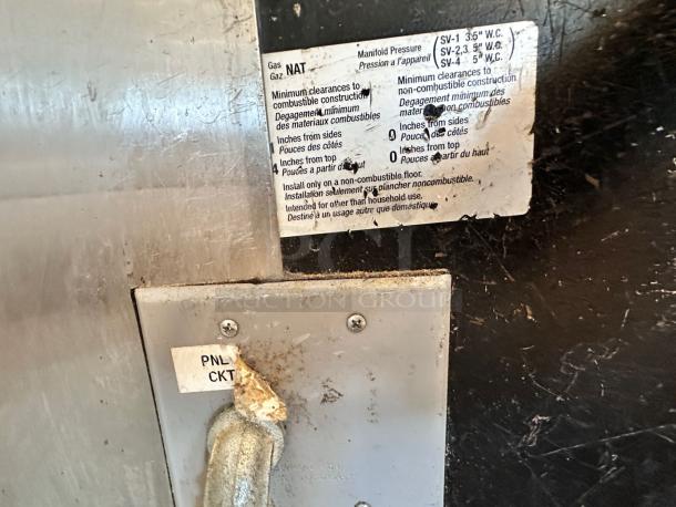 Alt text: Metal panel of Wood Stone Mt. Adams 9660 pizza oven with labels indicating natural gas use and clearance instructions.