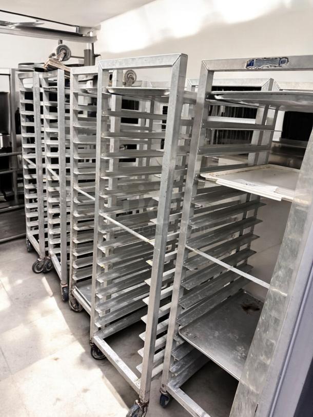 Full-height mobile pan racks by Alexander Industries in excellent condition, NSF certified, featuring multiple slots and caster wheels.