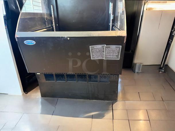 Black industrial equipment with Federal branding, featuring a transparent panel and warning labels. Flooring visible.