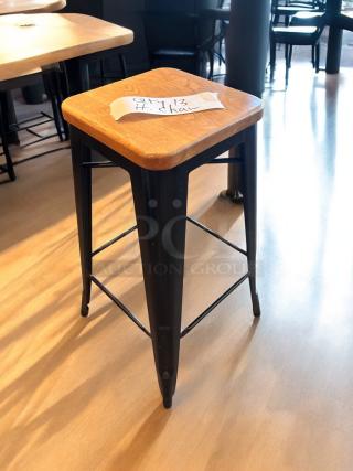 Industrial bar-height stool with a solid wood seat and matte black steel frame, excellent condition. Tag reads "Qty 13 H. chair".