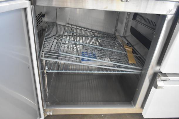 Brand new Avantco 178SSWD3R stainless steel worktop refrigerator interior, showing shelves, minor scratches visible.