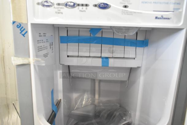 Brand new 2023 Manitowoc UCP0050A-161 ice machine, 52 lb. capacity, with protective tape and labels visible inside.