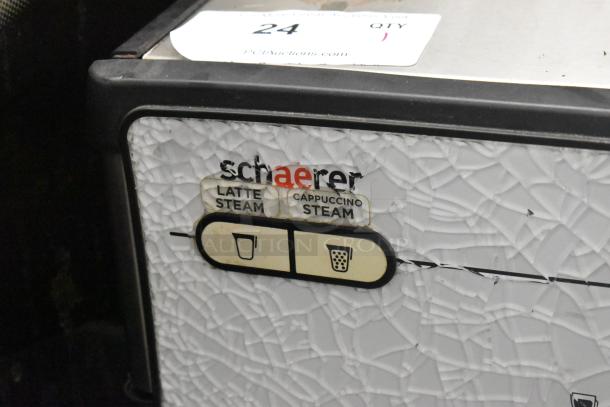 Schaerer Barista espresso machine feature panel with latte and cappuccino steam buttons; surface shows visible damage.