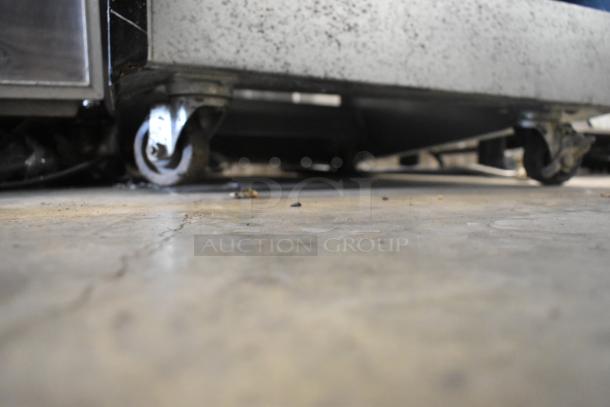 BKI HSS2-4T metal merchandiser on commercial casters, 208V, 1 phase. Close-up of casters indicates mobility.