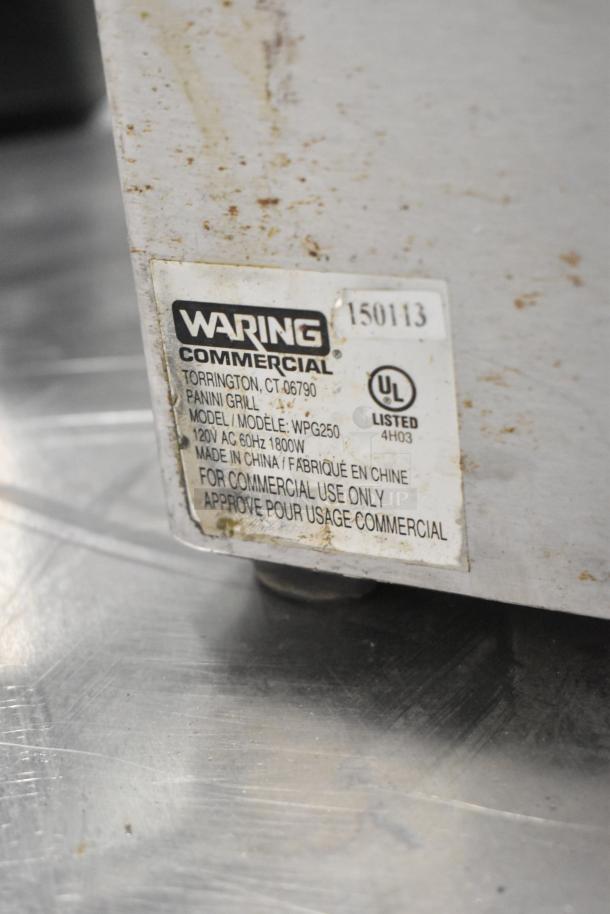 Waring WPG250 stainless steel commercial panini press, 120V, with visible model label, showing wear on the exterior.