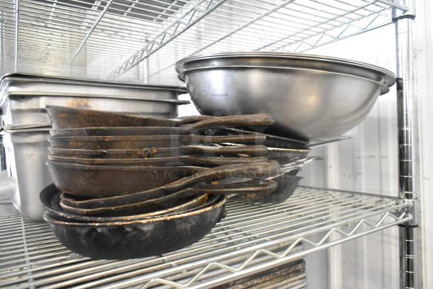 Tiered lot of kitchen items including stainless steel drop-in bins, skillets, and metal bowls; signs of wear visible.