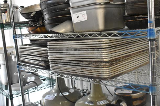 Tiered shelving with assorted metal baking pans and kitchenware, showing wear. Tag: "41, QTY Tier lot, PCIAuctions.com."