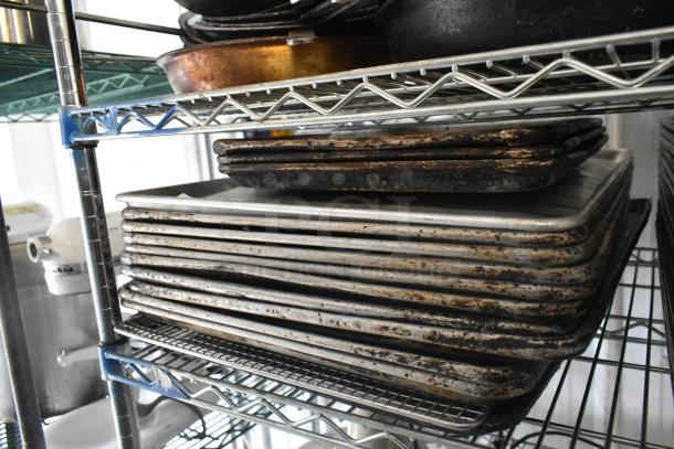 Alt text: Stack of metal baking pans on a wire shelf, showing wear from use, part of a mixed item auction lot.