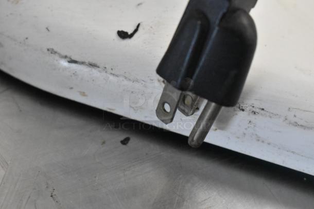 Close-up of a KitchenAid dough mixer plug. Some wear and dirt visible on the metal surface.