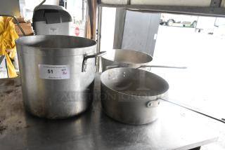 Three metal kitchen items: a large stock pot and two sauce pans with handles. Visible tag reads "51, QTY 3v, PCIAuctions.com."