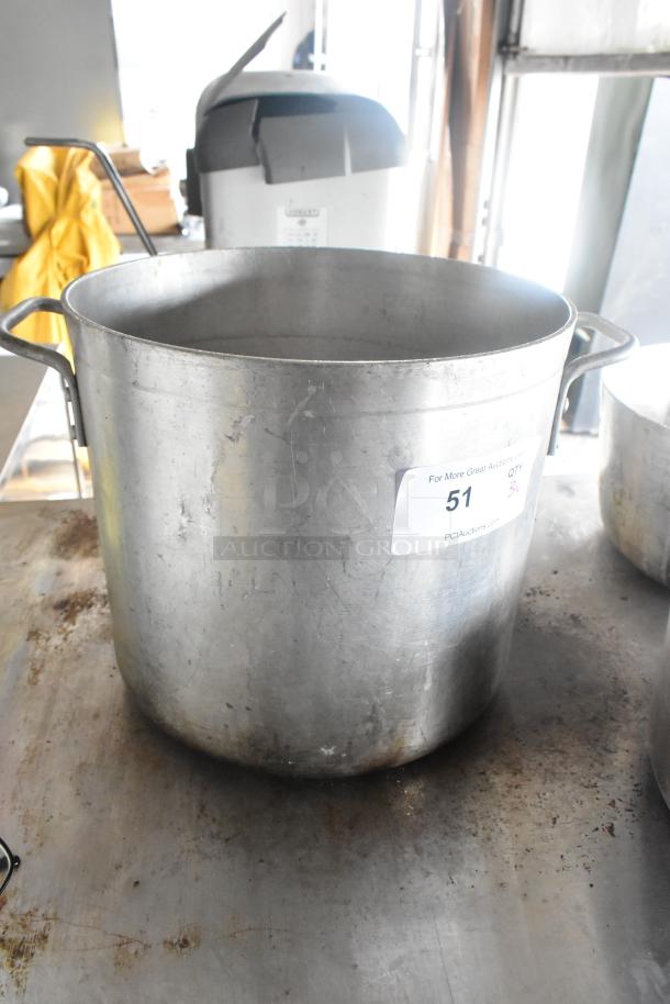 Large metal stock pot with visible wear, accompanied by two sauce pans. Auction label indicates lot number 51.