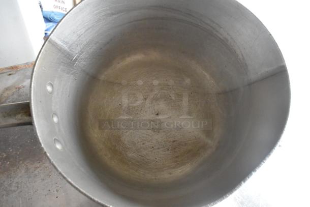 Three metal items, including a stock pot and two saucepans. Visible wear, scratches inside. No visible labels or markings.