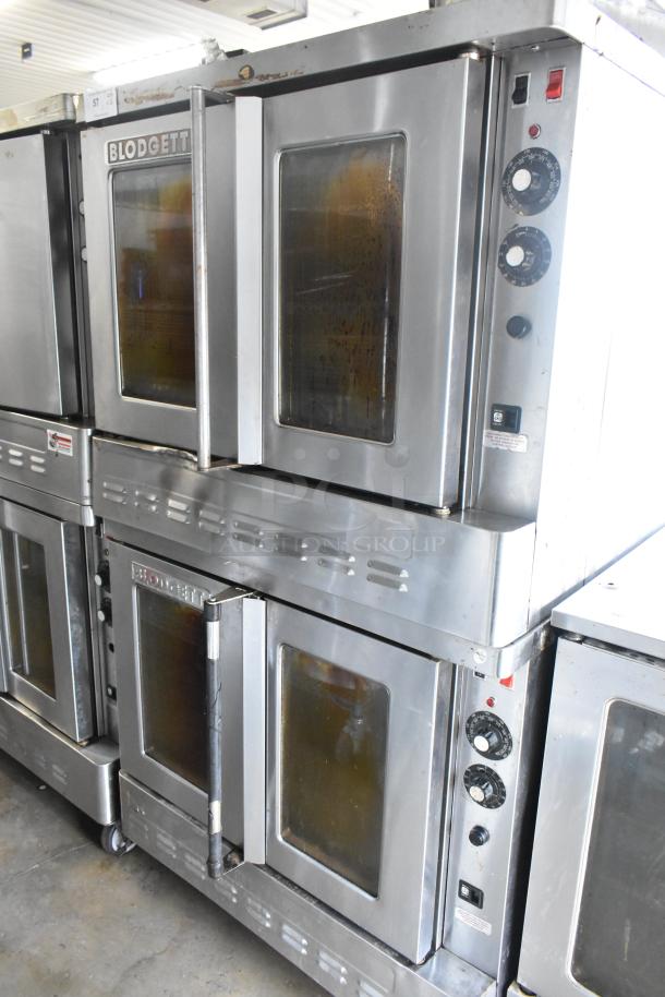 2 Blodgett stainless steel gas convection ovens with view-through doors, metal racks, thermostatic controls, on casters.