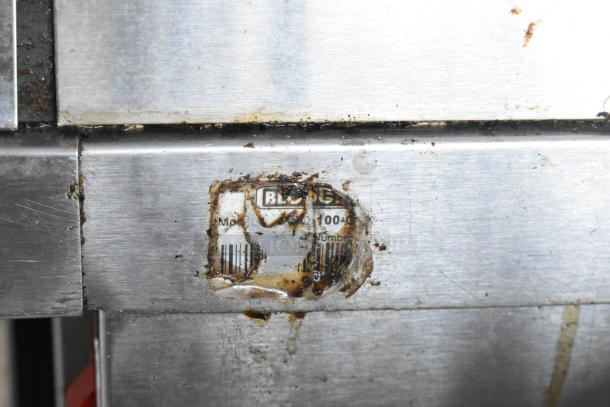 Blodgett SHO-100-G oven label, partially obscured, on stainless steel surface, showing model and number details.