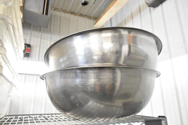 Lot of poly clear bins and stainless steel metal bowls on a shelving unit. Bins stacked; bowls show reflective finish.