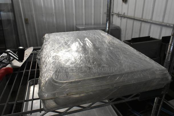 Lot of 3 poly clear lids wrapped in plastic on a metal rack, in good condition; suitable for storage or food service use.