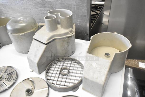 11 various kitchen appliance parts including a continuous feed head, bowls, S blades, slicing, and grating blades in used condition.