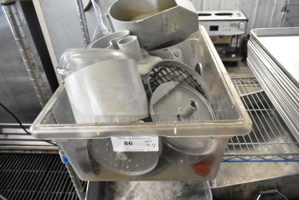 11 kitchen items including a continuous feed head, 2 bowls, 2 S blades, 3 slicing and 3 grating blades in a bin.