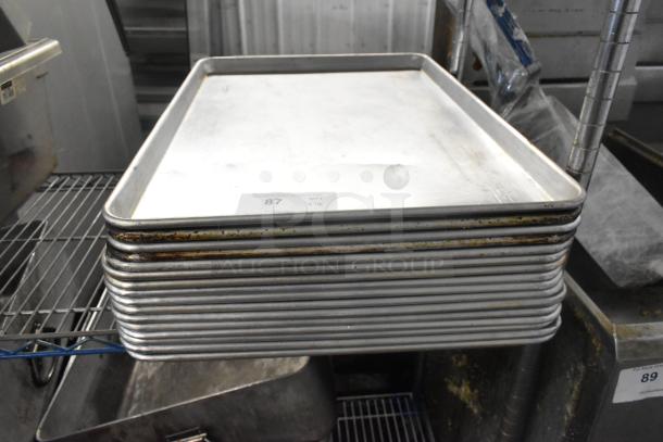 Stack of 16 full-size metal baking pans, slightly worn, auction lot 87, marked "QTY x16."