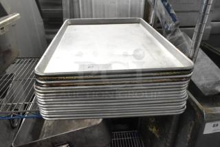 Stack of 16 full-size metal baking pans, slightly worn, auction lot 87, marked "QTY x16."