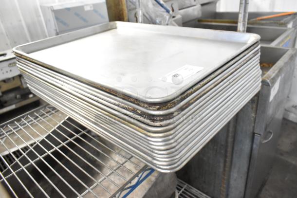 Stack of 16 metal full-size baking pans with visible wear. Auction lot tag marked "87". Suitable for bulk baking needs.