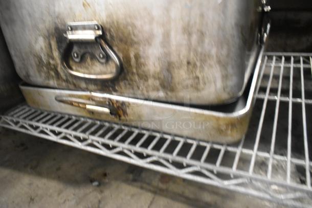 Eight metal pans with handles on wire rack, showing wear and discoloration, ideal for bulk cooking.