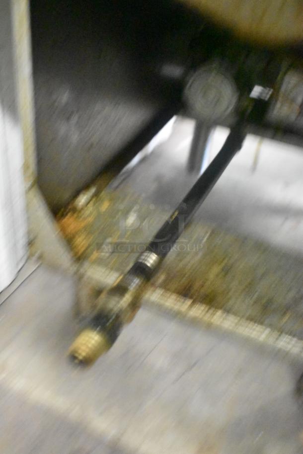 Blurred image of a gas connection under a Cecilware Pro stainless steel commercial fryer.