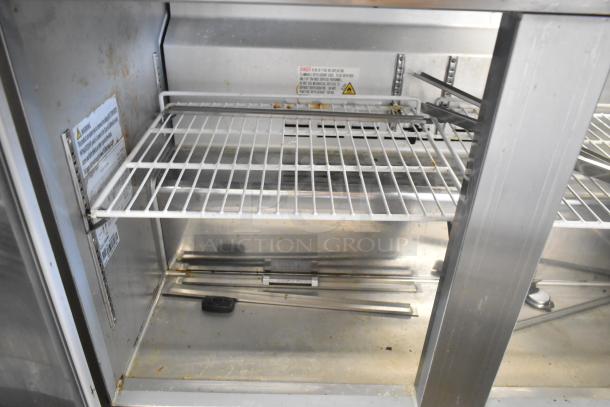Coldline SMP48 stainless steel prep table interior, showing shelving and sneeze guard supports; some signs of wear.