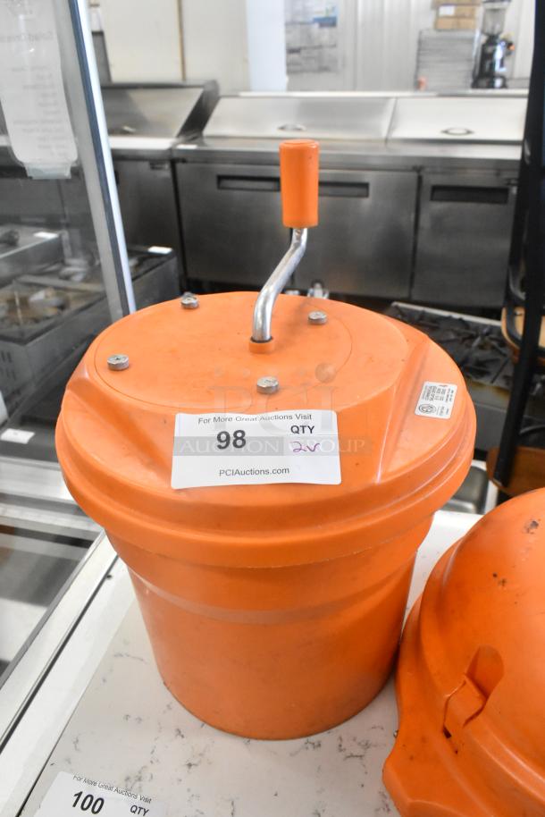 Orange salad spinner with handle, paired with a Dynacube vegetable cutter. Both items are in used condition, labeled with auction details.