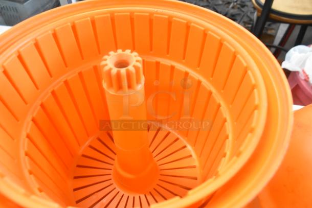 Orange salad spinner with internal basket and gear mechanism, in good condition, part of a set with Dynacube vegetable cutter.