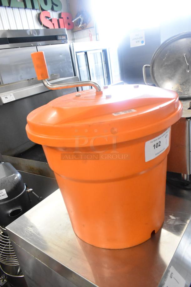 Orange poly lettuce spinner with manual handle, good condition, visible auction label "102". Ideal for restaurant use.