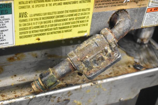 Vulcan stainless steel commercial griddle gas connector, worn and corroded, with safety warning labels in French and English.
