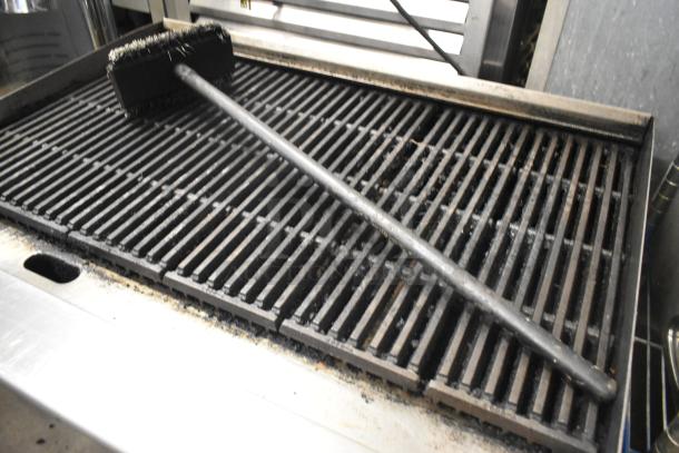 Migali stainless steel commercial countertop gas charbroiler grill with visible cooking grates and cleaning brush.