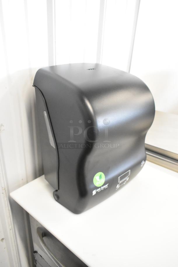 Brand new San Jamar black poly paper towel dispenser, minor scratches, features eco label and durable design.
