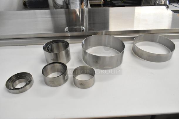 13 brand new Fat Daddio's stainless steel round cake molds, varying sizes, high-quality, durable, minor scratches.