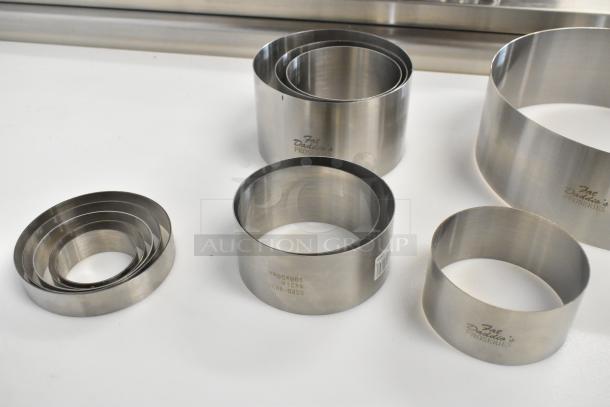 Set of 13 Fat Daddio's stainless steel round cake/food ring molds, new with minor scratches and dents, branding visible.