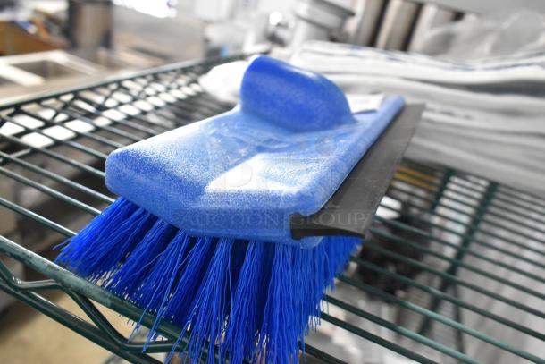 Blue brush head with sturdy bristles on metal rack, part of 4 new Lavex 24" mop pads and brush heads, Choice brand.