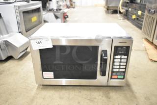 Brand new Panasonic NE-1054F commercial microwave oven, stainless steel, 120V, 1 phase, slight scratch and dent, model label visible.