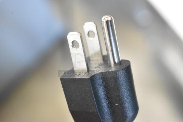 Close-up of a power plug for the Avantco 177HDC26 heated display case. Black plug with metal prongs, designed for 120 volts.