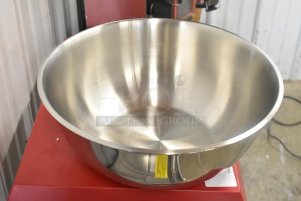 Stainless steel Winco MXBH-1300 mixing bowl, brand new, reflecting light, placed on a red surface.
