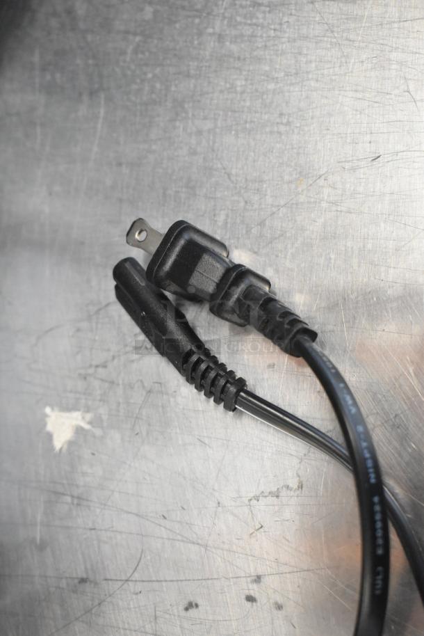 Power cables on a metal surface, possibly for electronics such as a Toshiba monitor or HP Pavilion computer.