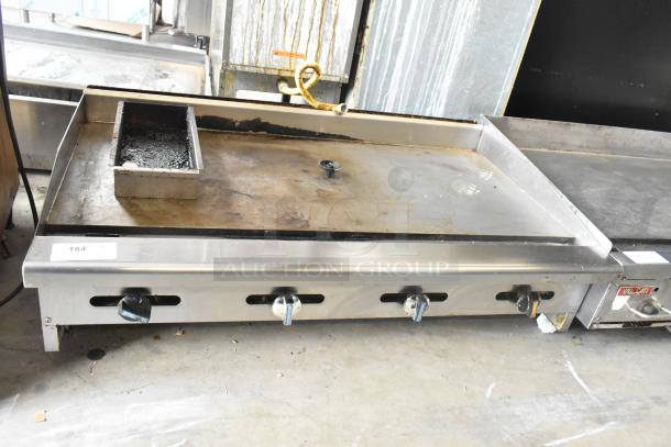 Radiance stainless steel commercial countertop gas griddle with four control knobs. Visible wear on cooking surface. Model 184 tag displayed.