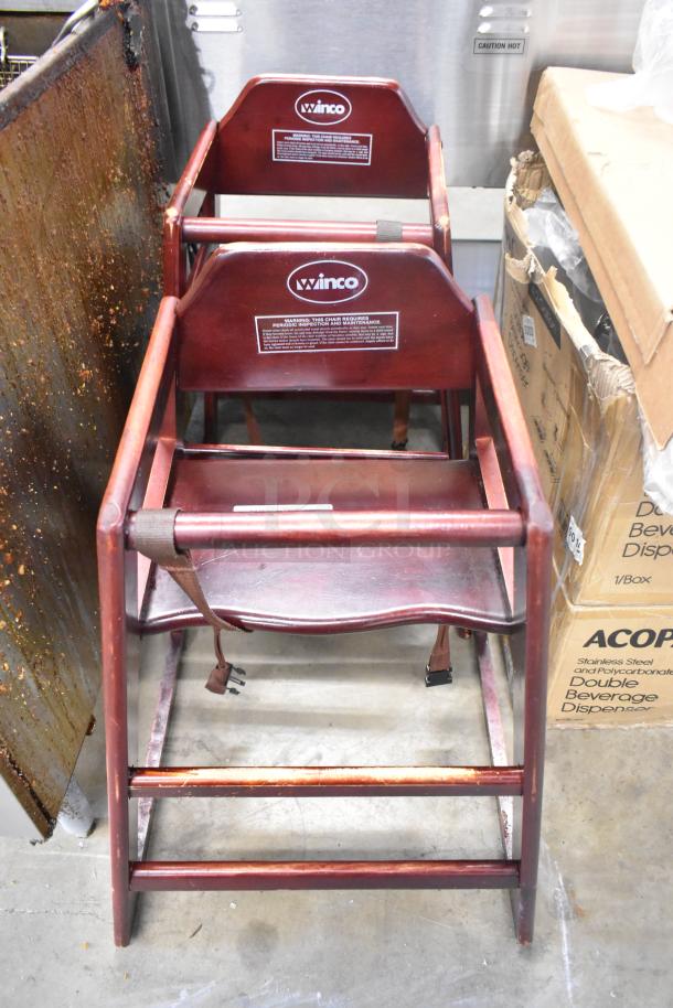 Pair of Winco wood high chairs with harness, wood pattern finish, durable design. Labels indicate inspection requirements.